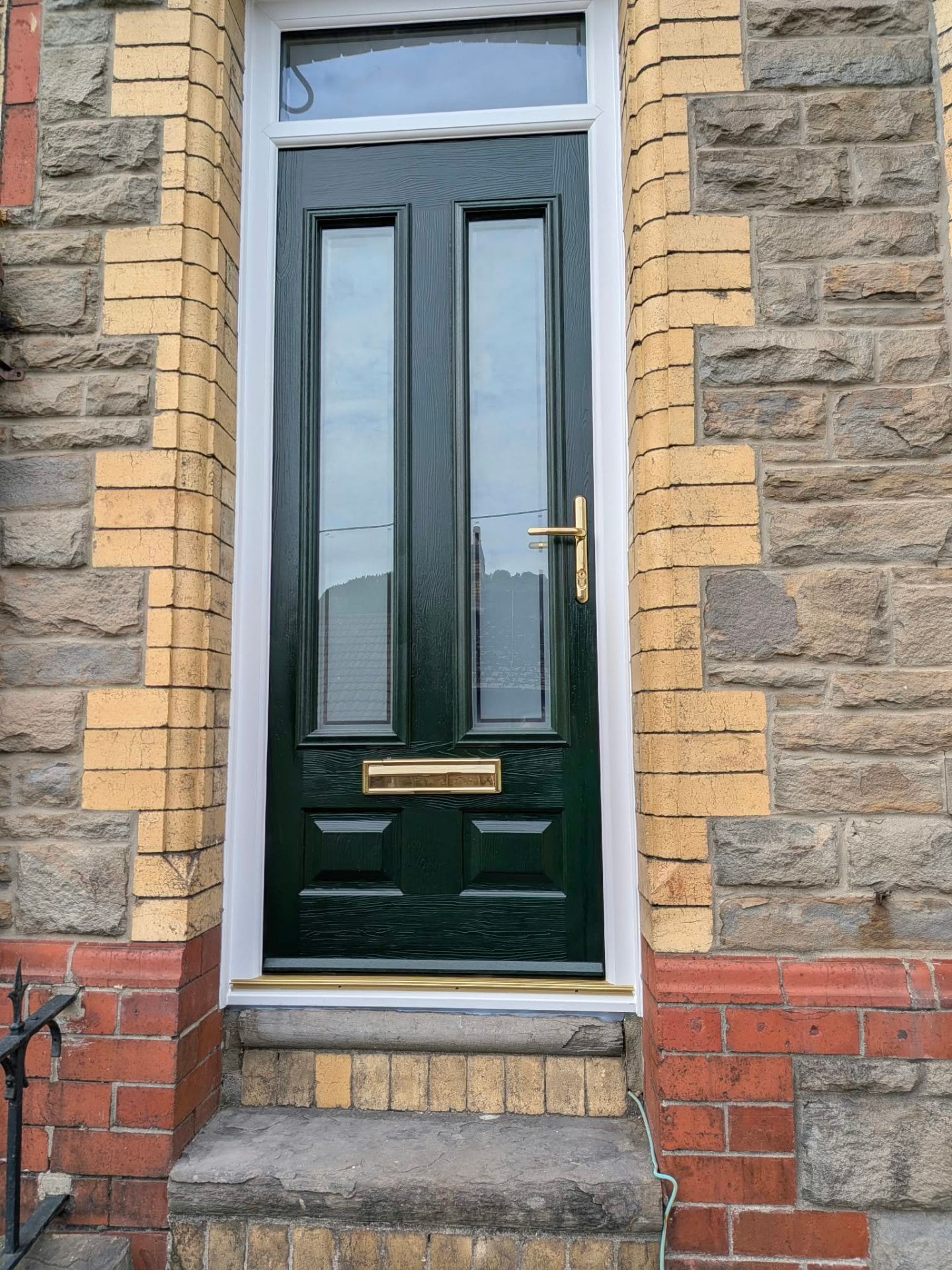 Green composite front door with gold hardware by Essential Glazing Products