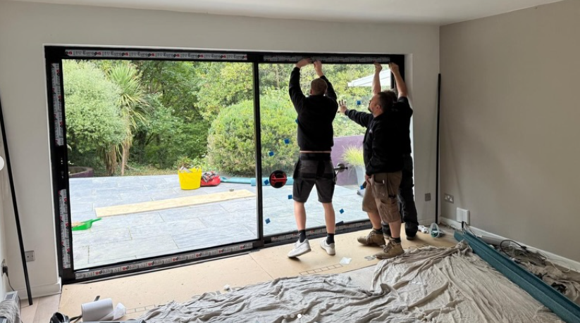 Essential Glazing Products fitters installing a large aluminium sliding door in a South Wales home